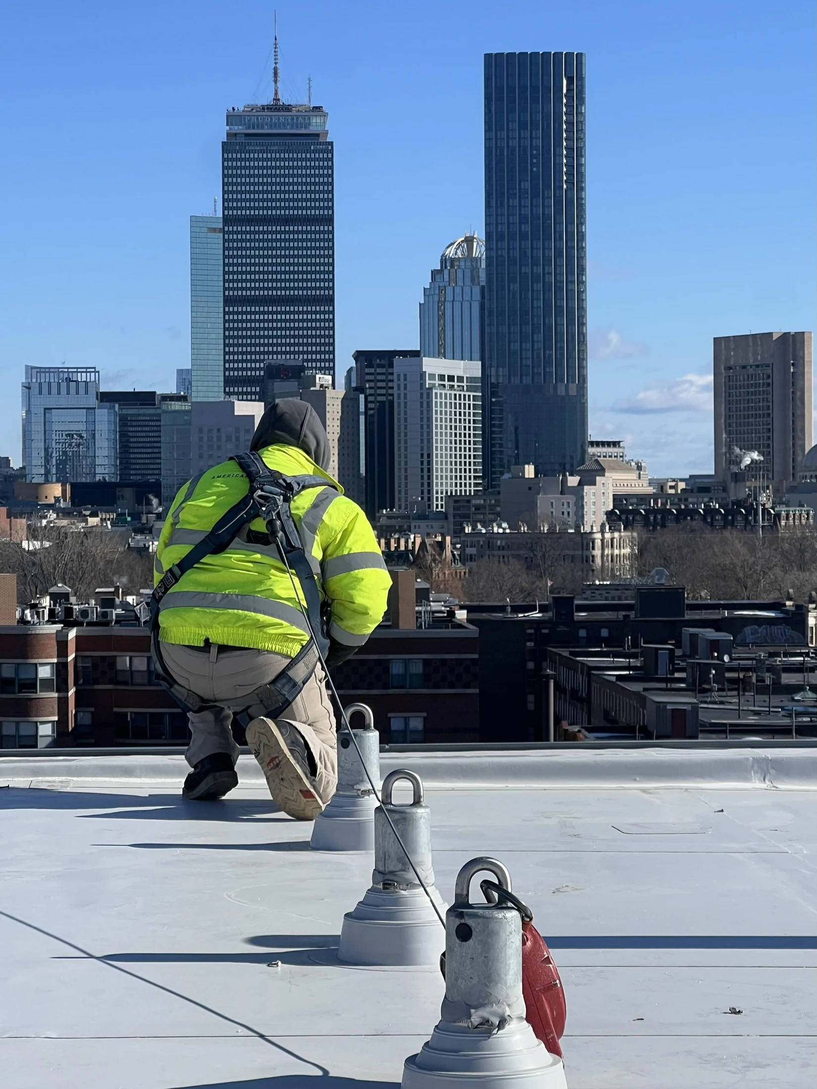 American Anchor technician tied off to rooftop anchor points above Boston
